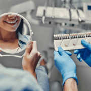 Patiente observant la teinte de ses dents avec un nuancier chez le dentiste