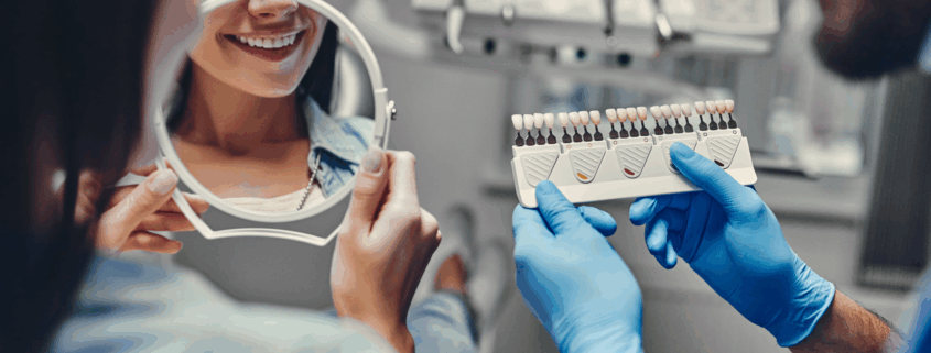 Patiente observant la teinte de ses dents avec un nuancier chez le dentiste
