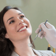 Femme souriante recevant un contrôle dentaire avec un miroir intra-oral