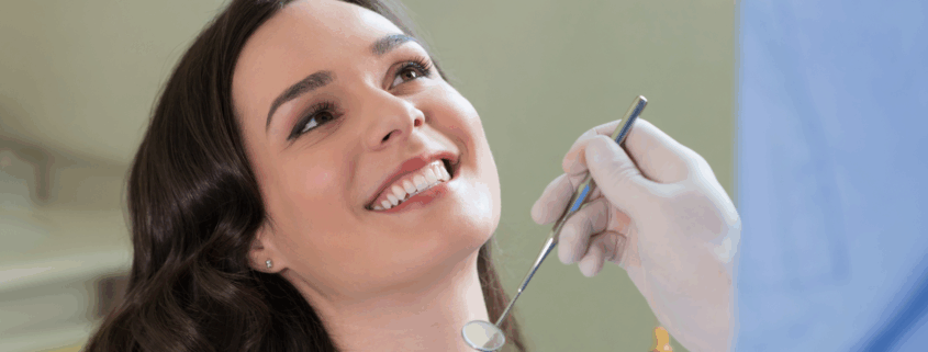 Femme souriante recevant un contrôle dentaire avec un miroir intra-oral
