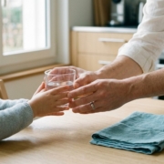Parent tendant un verre d'eau à un jeune enfant assis à table