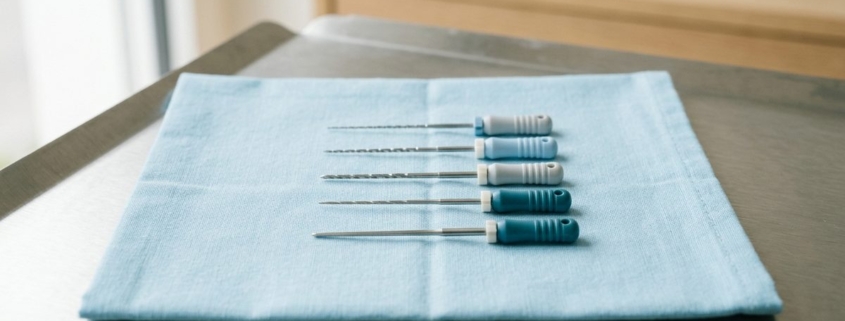 Instruments d'endodontie alignés sur un champ stérile bleu